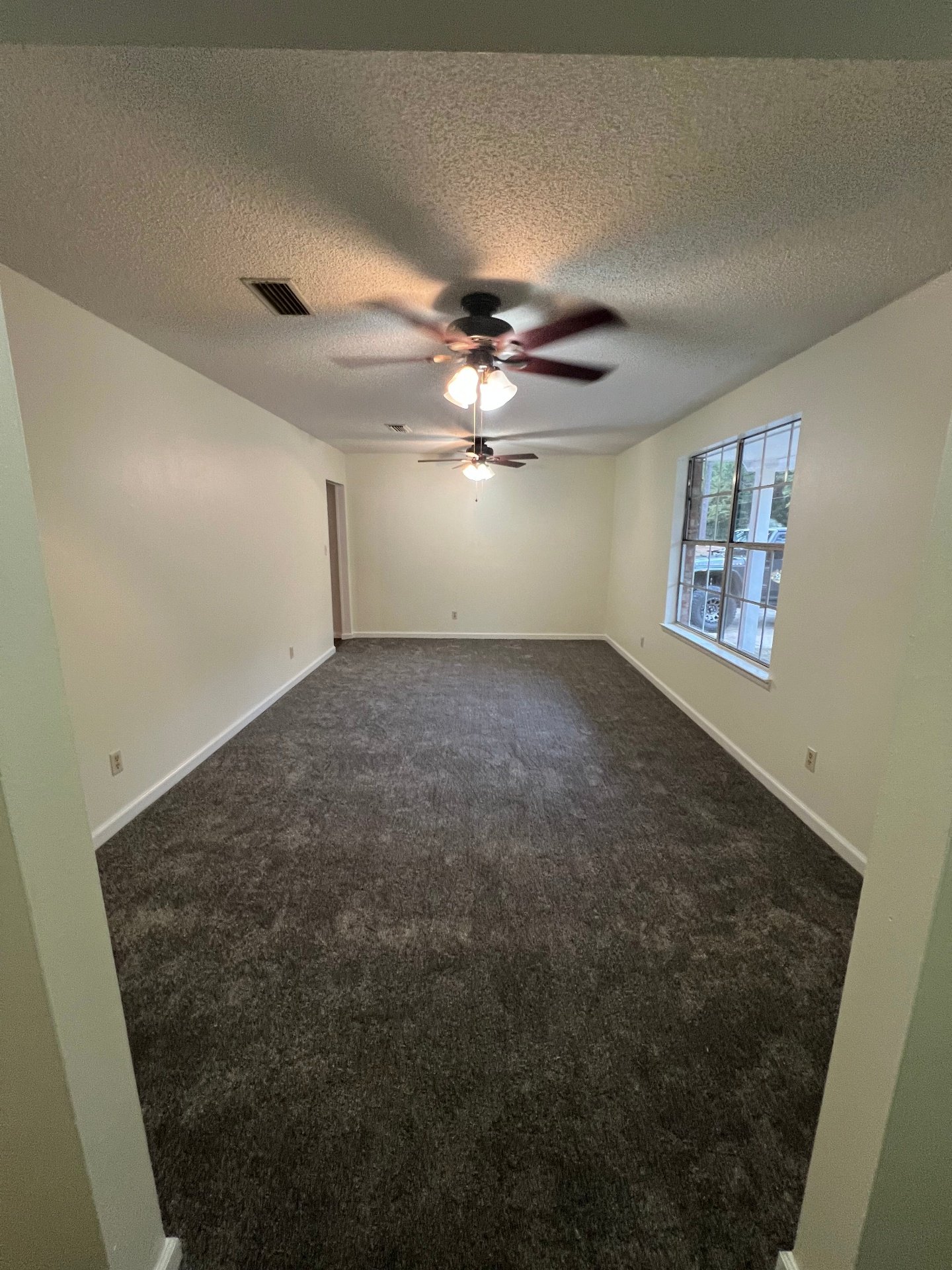 Large living room carpet installation with dual ceiling fans featuring stain-resistant gray carpet flooring for family spaces