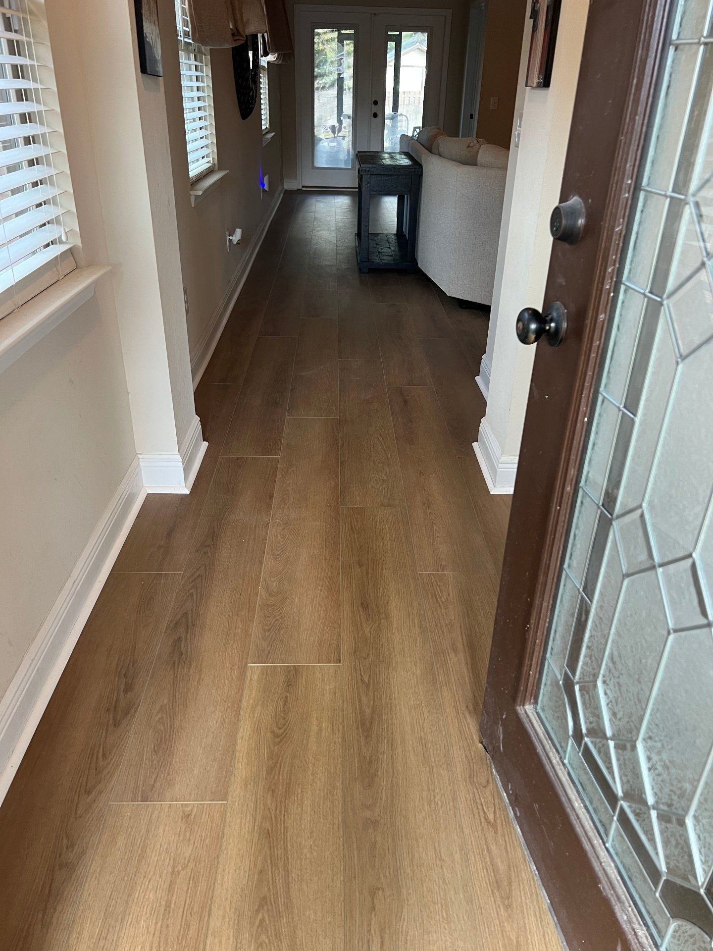 Luxury vinyl plank flooring installation in residential entryway with warm oak wood-look finish and professional trim work