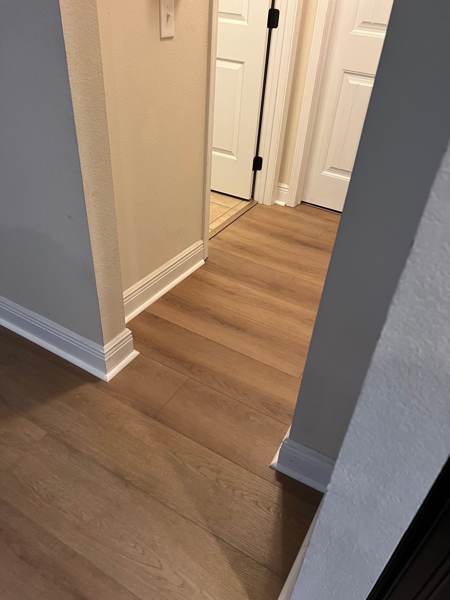 Hallway vinyl plank flooring installation with clean lines and professional basebaord trim in residential home