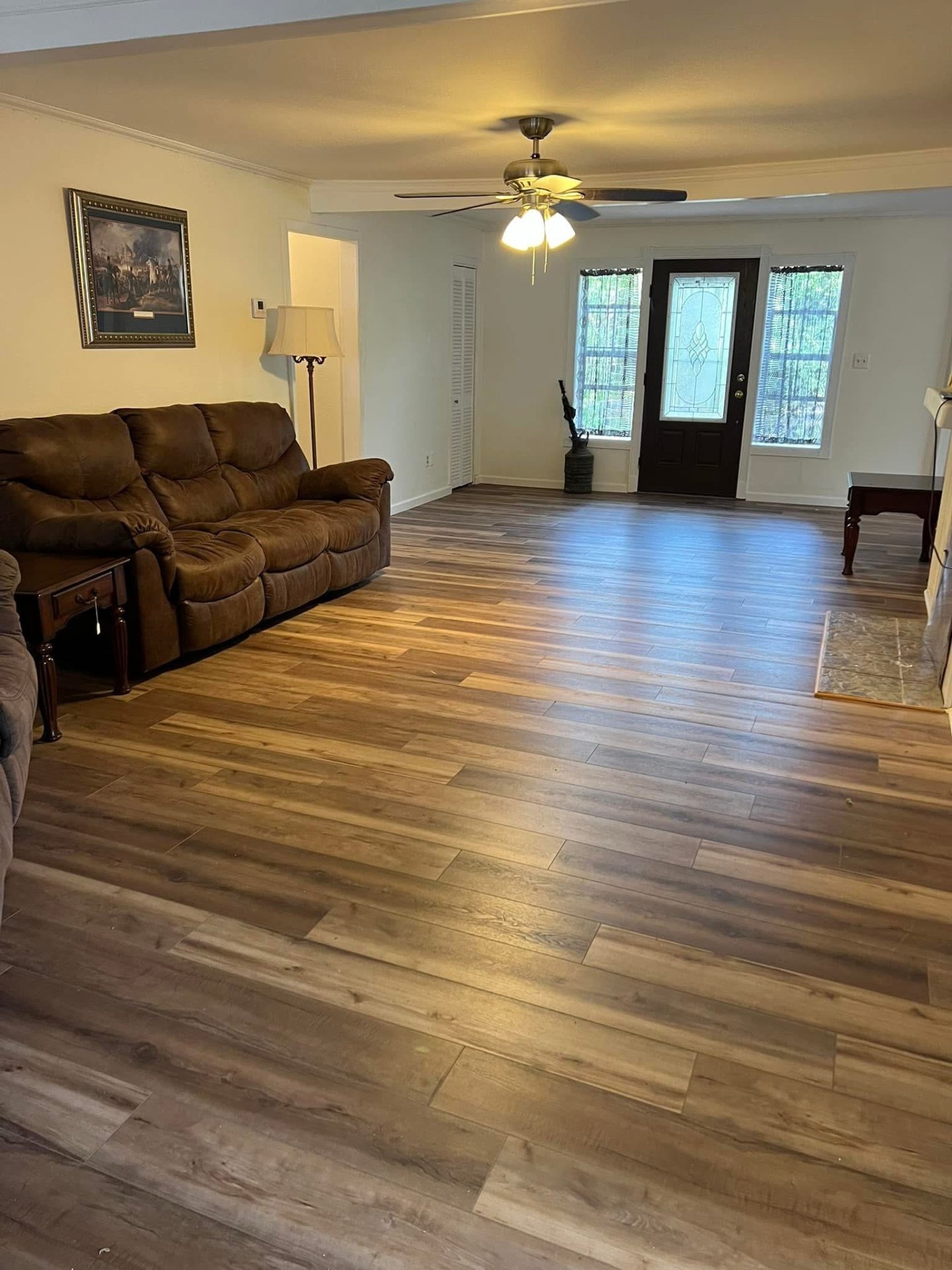 Spacious living room luxury vinyl plank flooring installation featuring warm natural wood-look LVP with comfortable furniture arrangement and modern home decor
