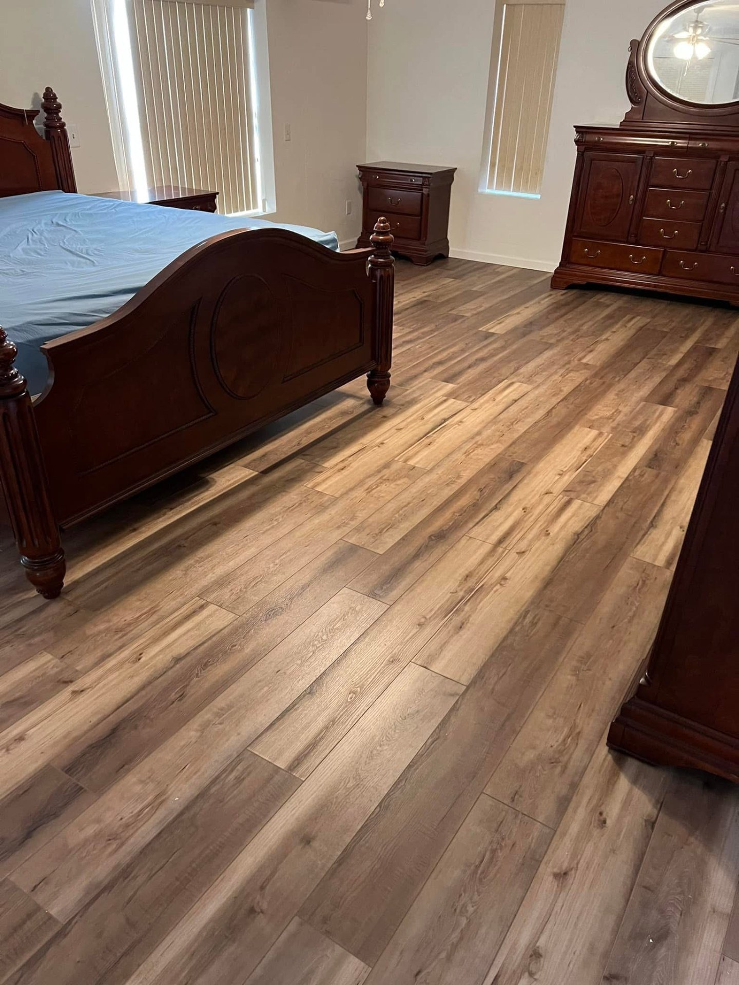 Master bedroom luxury vinyl plank flooring installation with warm oak tones professional wall-to-wall coverage and natural lighting